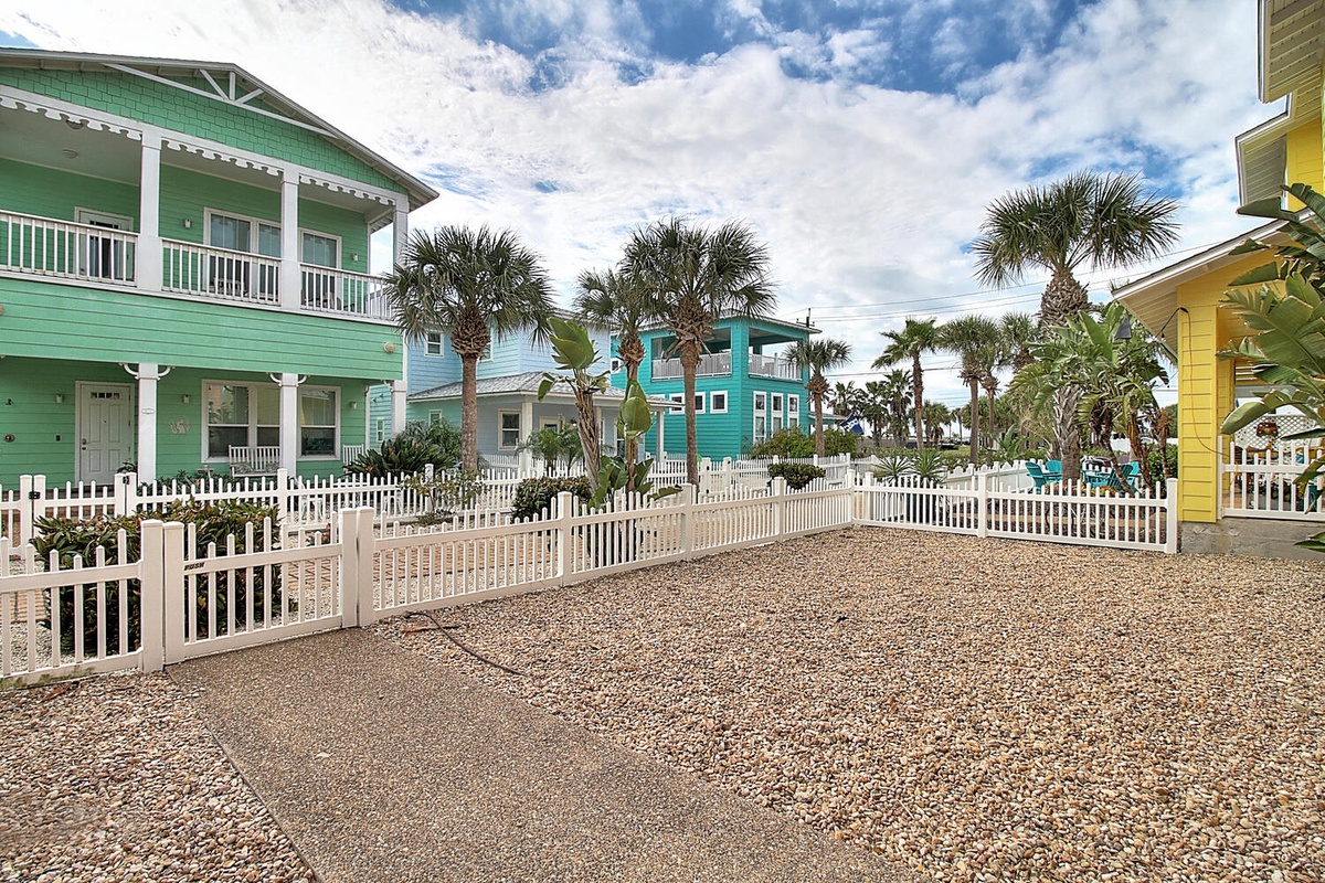 Charming beachside community with vibrant tropical cottages surrounded by swaying palm trees and white picket fences.
