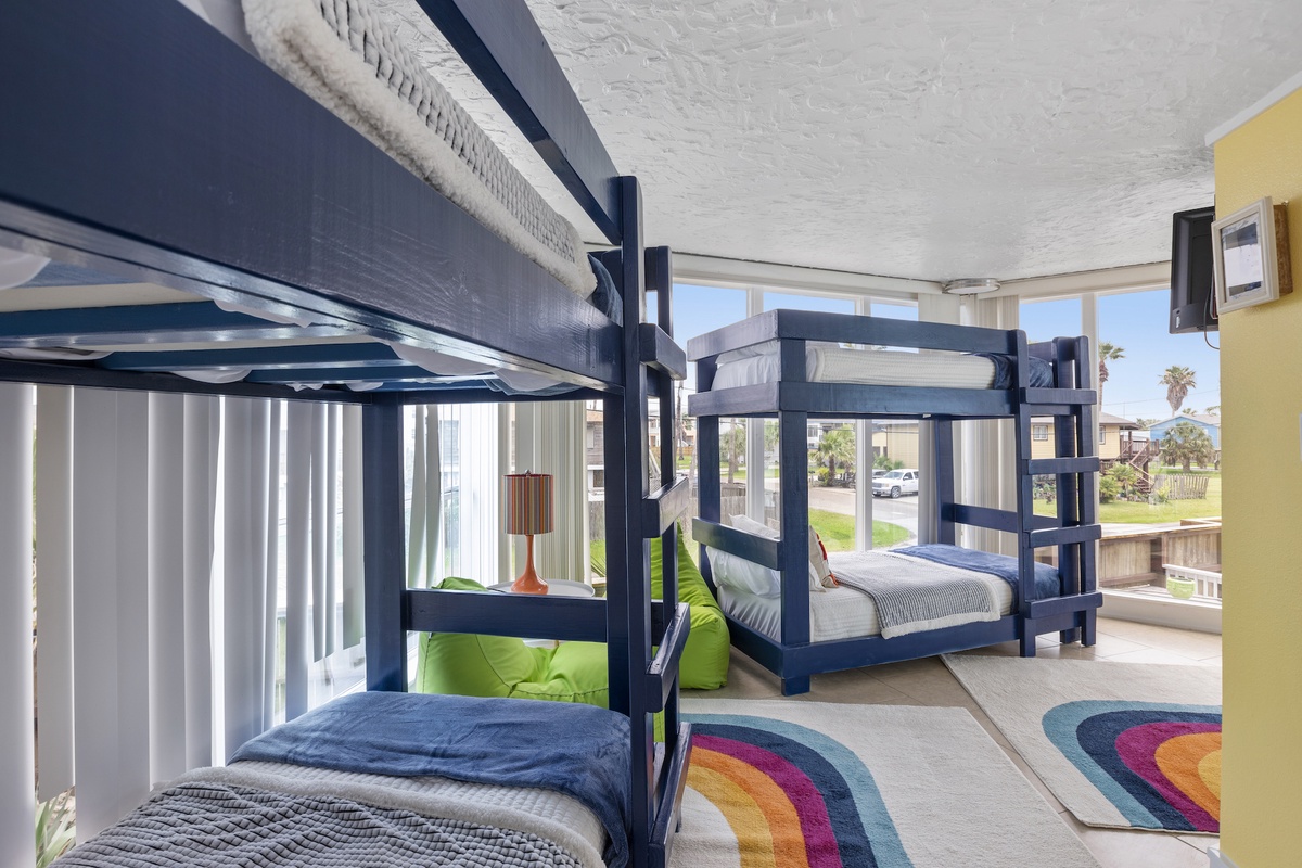 Your family can spread out in comfort with these sturdy navy bunk beds and colorful rainbow rug adding playful charm.