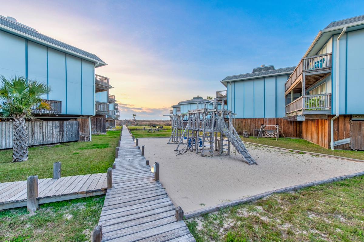 Coastal rental community featuring elevated beach houses with playground and boardwalk leading to pristine shoreline.