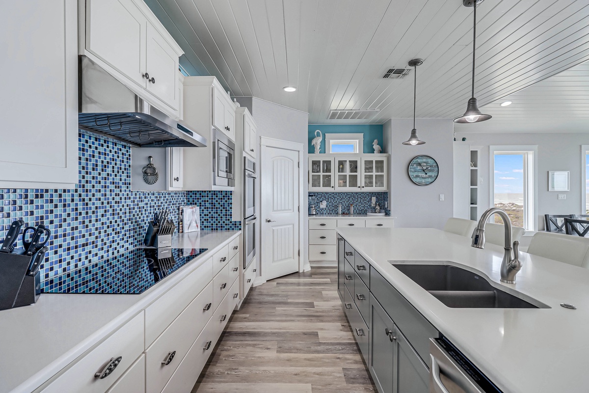 Cook your favorite meals in this beautiful coastal kitchen with stunning blue tile backsplash and modern appliances.