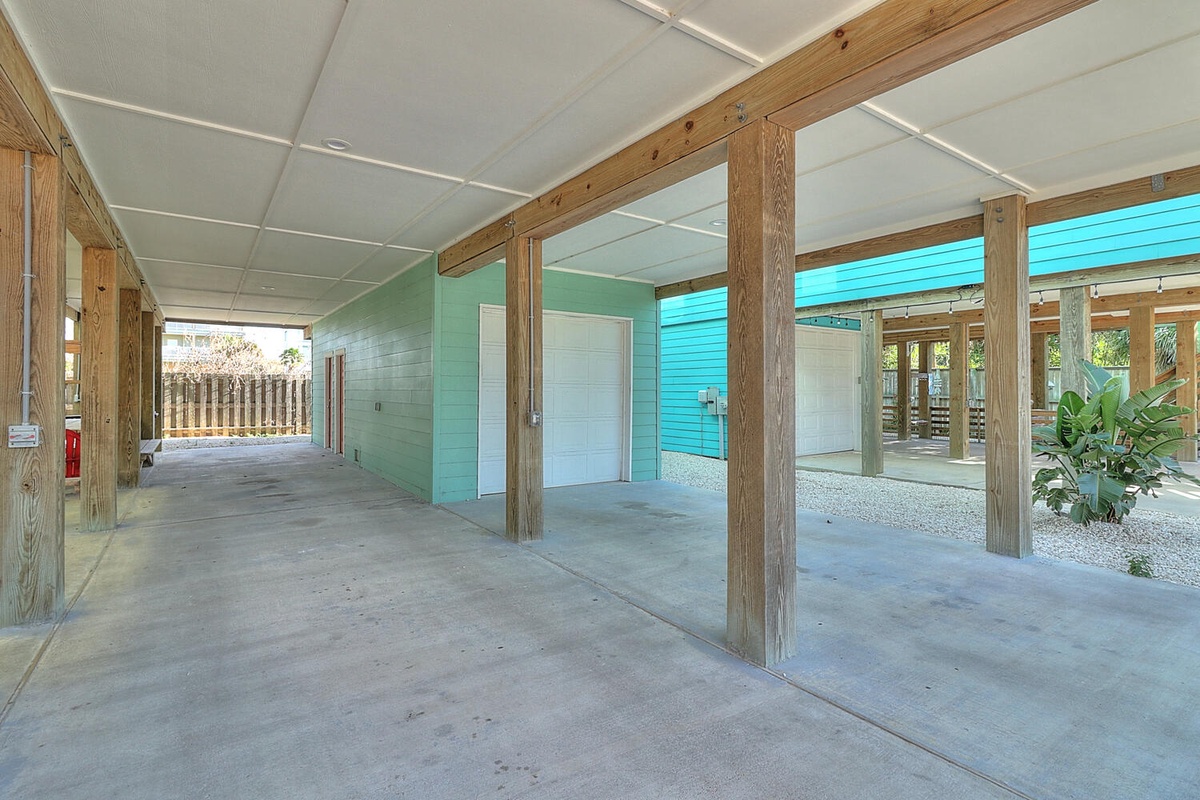 Covered parking area beneath property with concrete flooring and wooden beam construction.