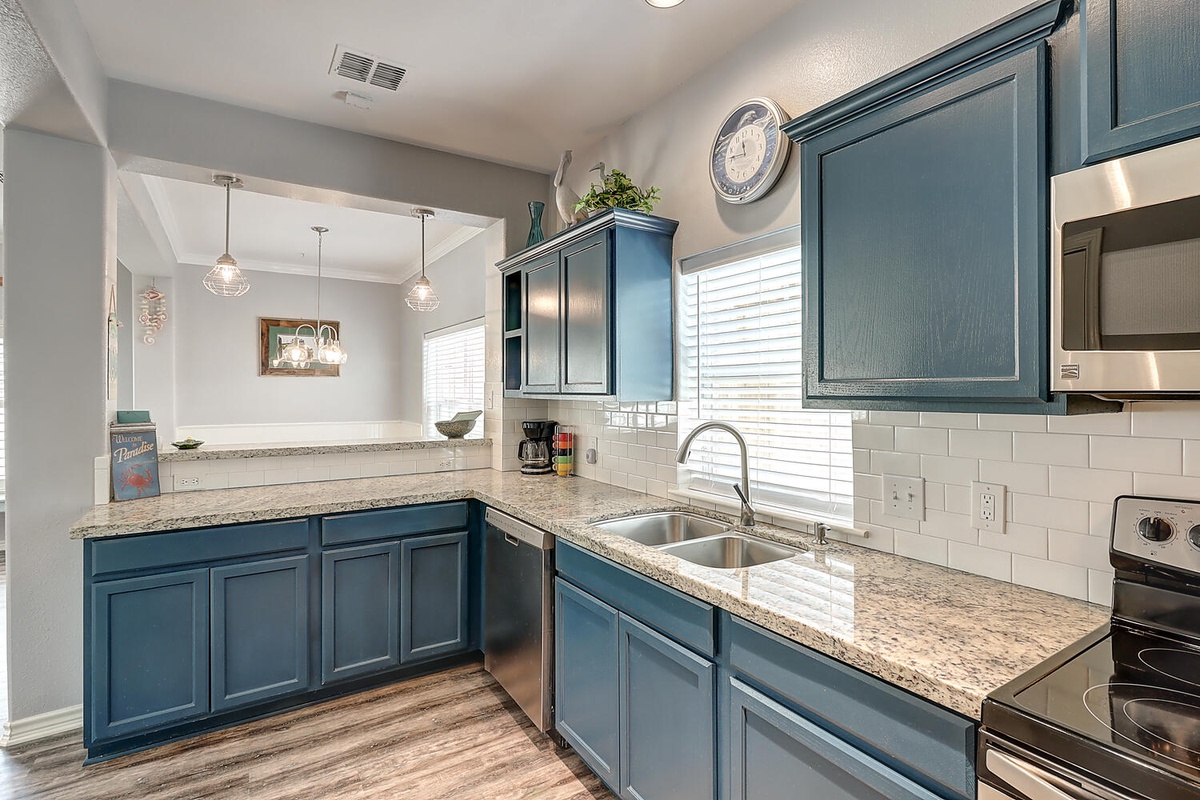 Your fully-equipped kitchen features beautiful blue cabinets, granite countertops, and stainless steel appliances for all your culinary adventures.