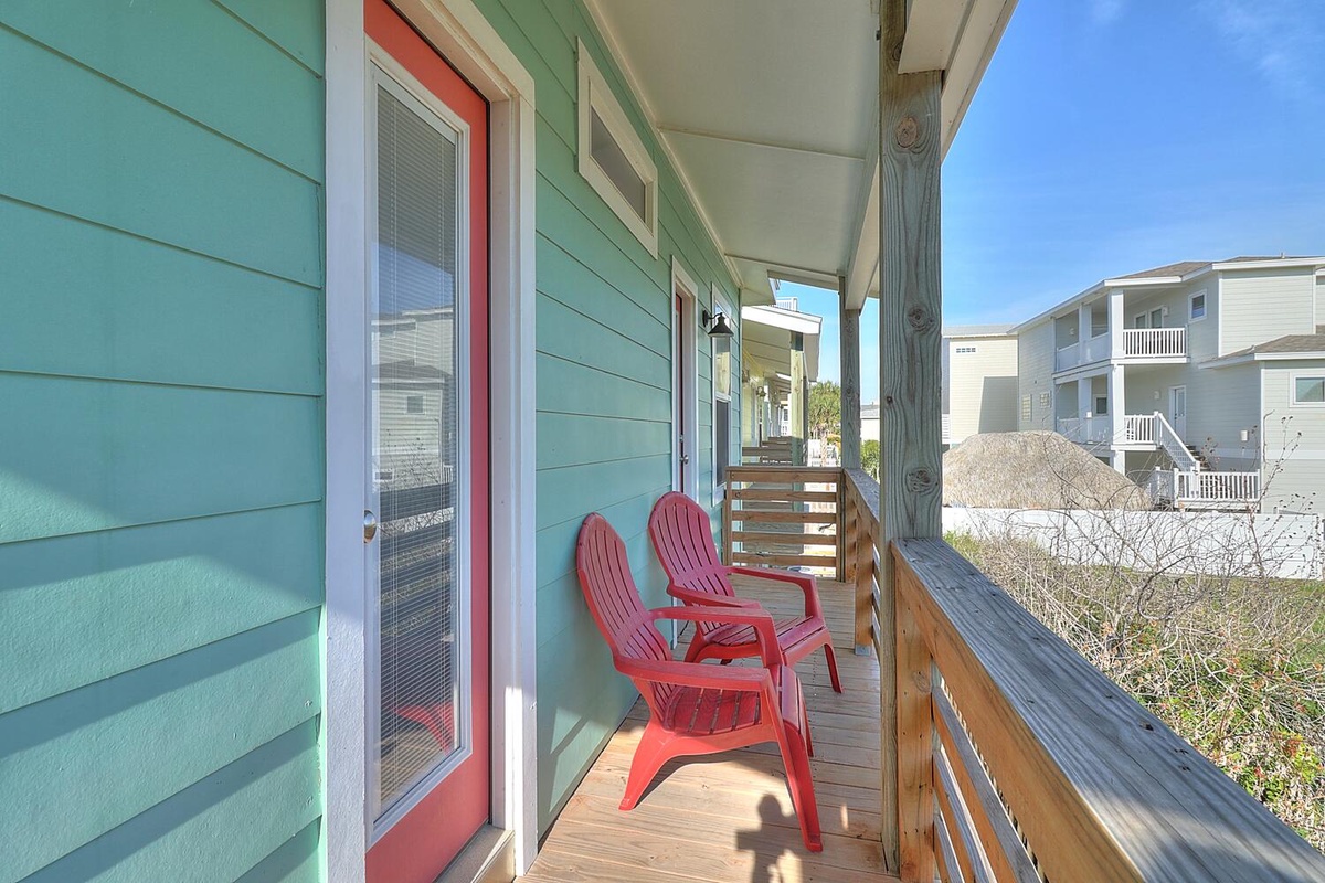 Relax on your private deck with cheerful coral chairs, soaking in coastal breezes and peaceful neighborhood views.