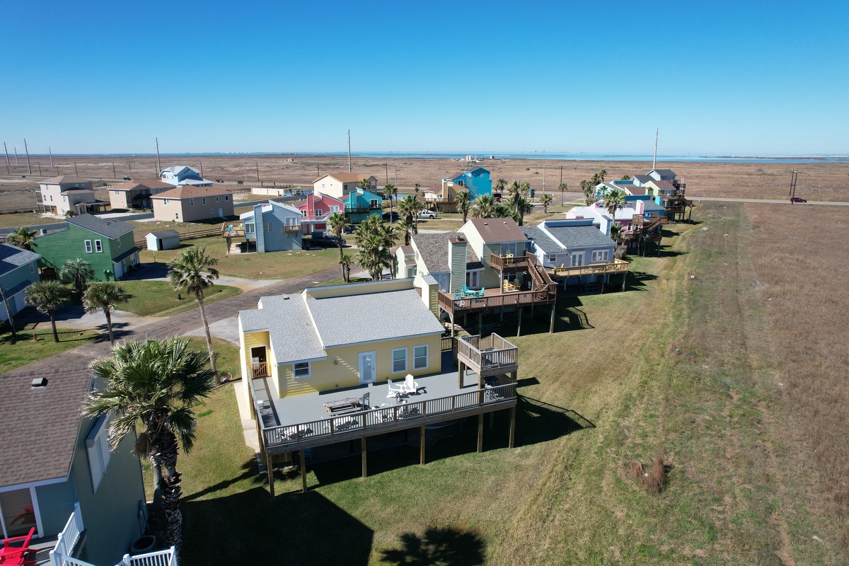 Coastal community of colorful vacation homes elevated on stilts, surrounded by natural marshland stretching to the horizon.