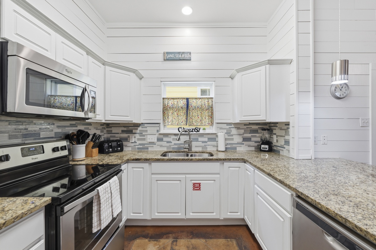 Your coastal-inspired kitchen features white shiplap walls, stylish granite counters, and all the appliances you need to whip up your favorite vacation meals.