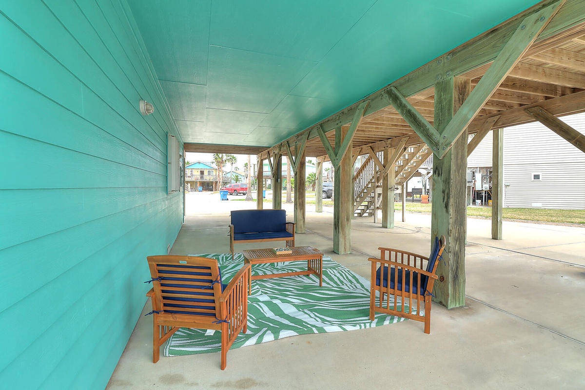 Relax in your private covered outdoor living space, featuring comfortable seating and tropical-themed decor beneath your beachside retreat.