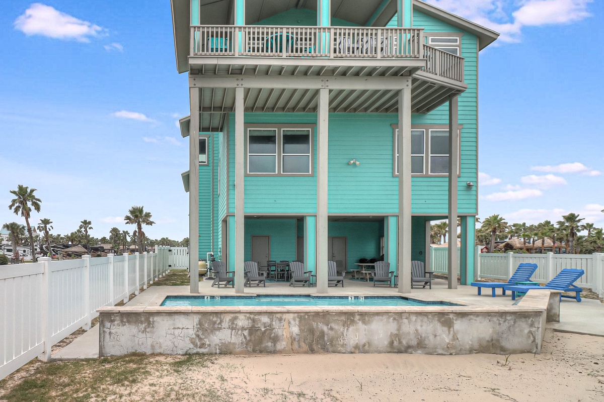 Coastal vacation home with private pool, covered patio seating, and tropical palm tree views in a beachside community.