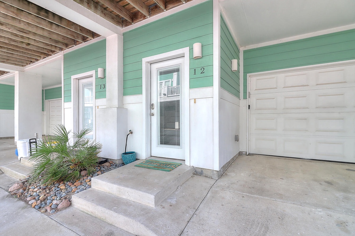 Charming beachside entrance with mint green siding and tropical landscaping welcomes guests to this coastal retreat.