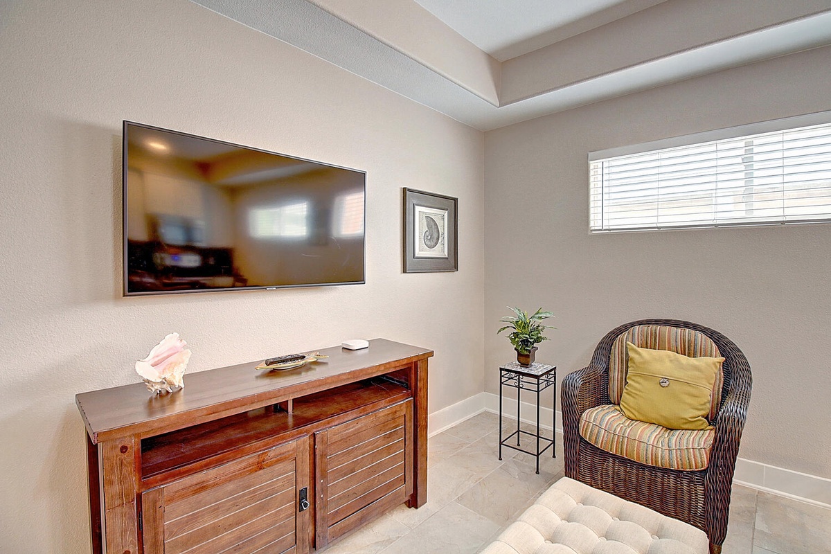 Unwind in your private retreat with a large wall-mounted TV and cozy wicker chair - perfect for quiet evenings in.