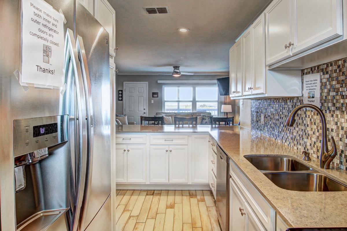 You'll love preparing meals in this bright, fully-equipped kitchen with gleaming countertops, modern appliances, and stylish mosaic backsplash.