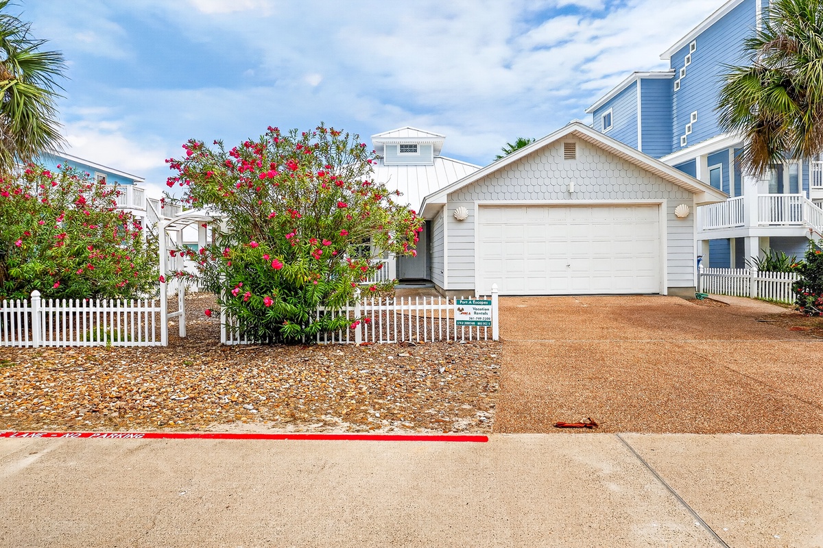 Coastal vacation home with tropical landscaping and garage, nestled in a charming beachside community.