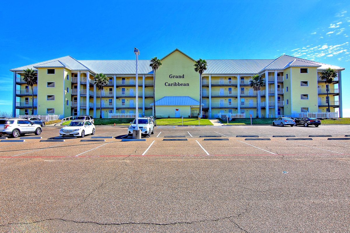 The Grand Caribbean resort welcomes guests with its distinctive yellow facade and convenient front parking area.