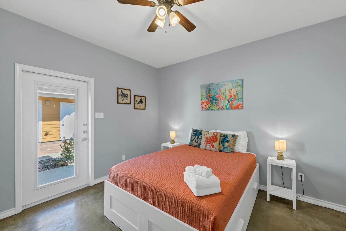 Drift off to peaceful sleep in your serene bedroom with coral bedding, nautical art, and gentle ceiling fan breeze.