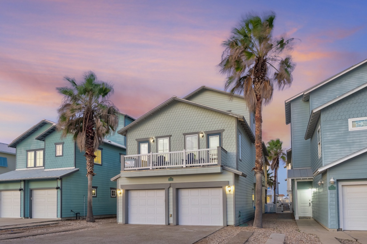 Charming coastal homes with palm trees create a perfect beachside retreat under stunning sunset skies.