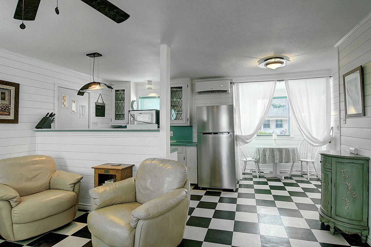 Relax in your charming cottage with vintage checkered floors, cozy seating, and a fully equipped kitchen overlooking peaceful neighborhood views.