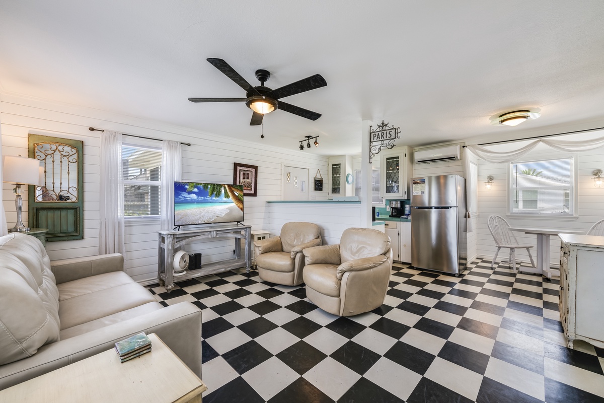 Step into your cozy retreat with charming checkered floors, plush seating, and a fully-equipped kitchen ready for your vacation meals and relaxation.