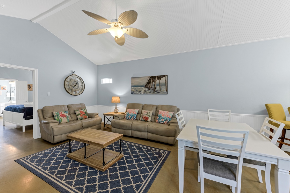Relax in your spacious open-plan living area with comfortable seating, coastal decor, and a ceiling fan to keep you cool during your stay.