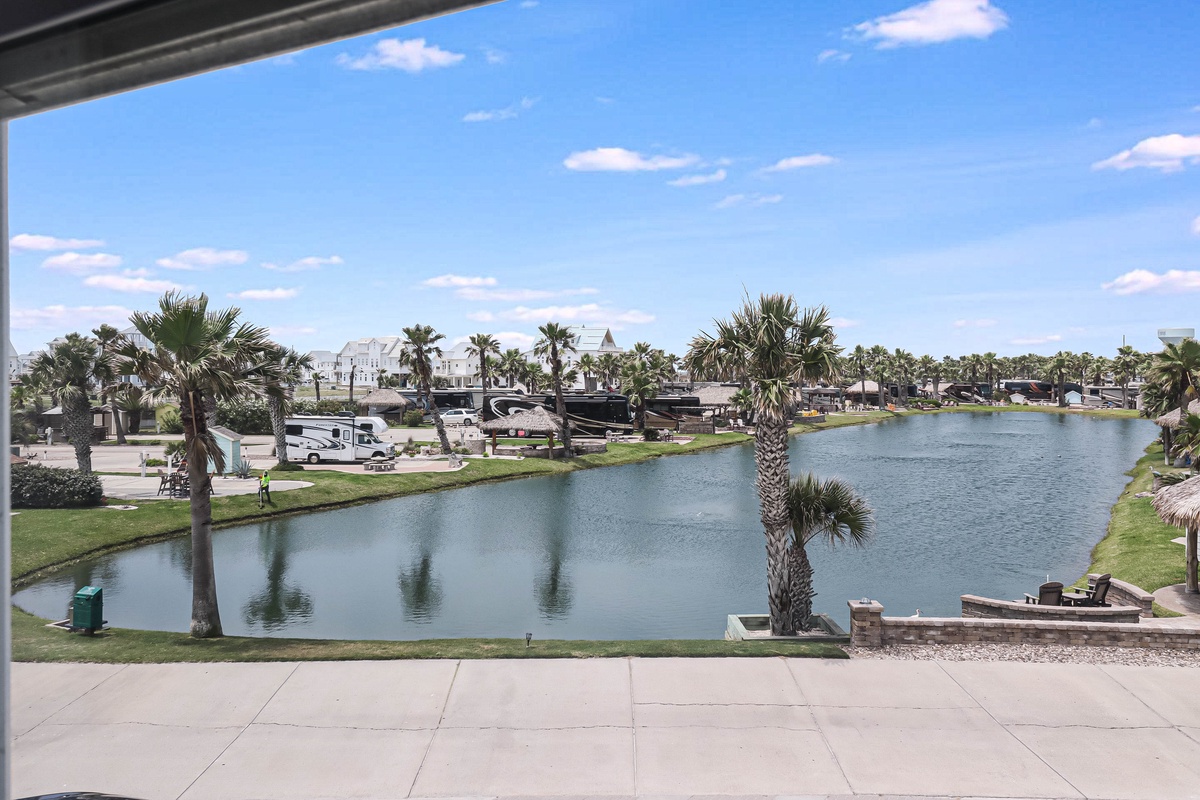 Scenic waterfront view with palm-lined canal and recreational vehicle park in a tropical setting.