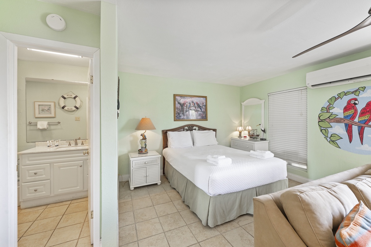 Relax in your tropical-themed bedroom with crisp linens, charming parrot artwork, and an ensuite bathroom for complete convenience.