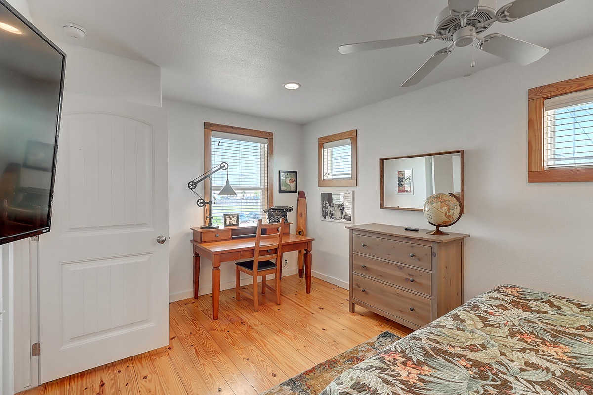 Your bright bedroom features a convenient workspace, dresser storage, and ceiling fan for perfect comfort during your stay.
