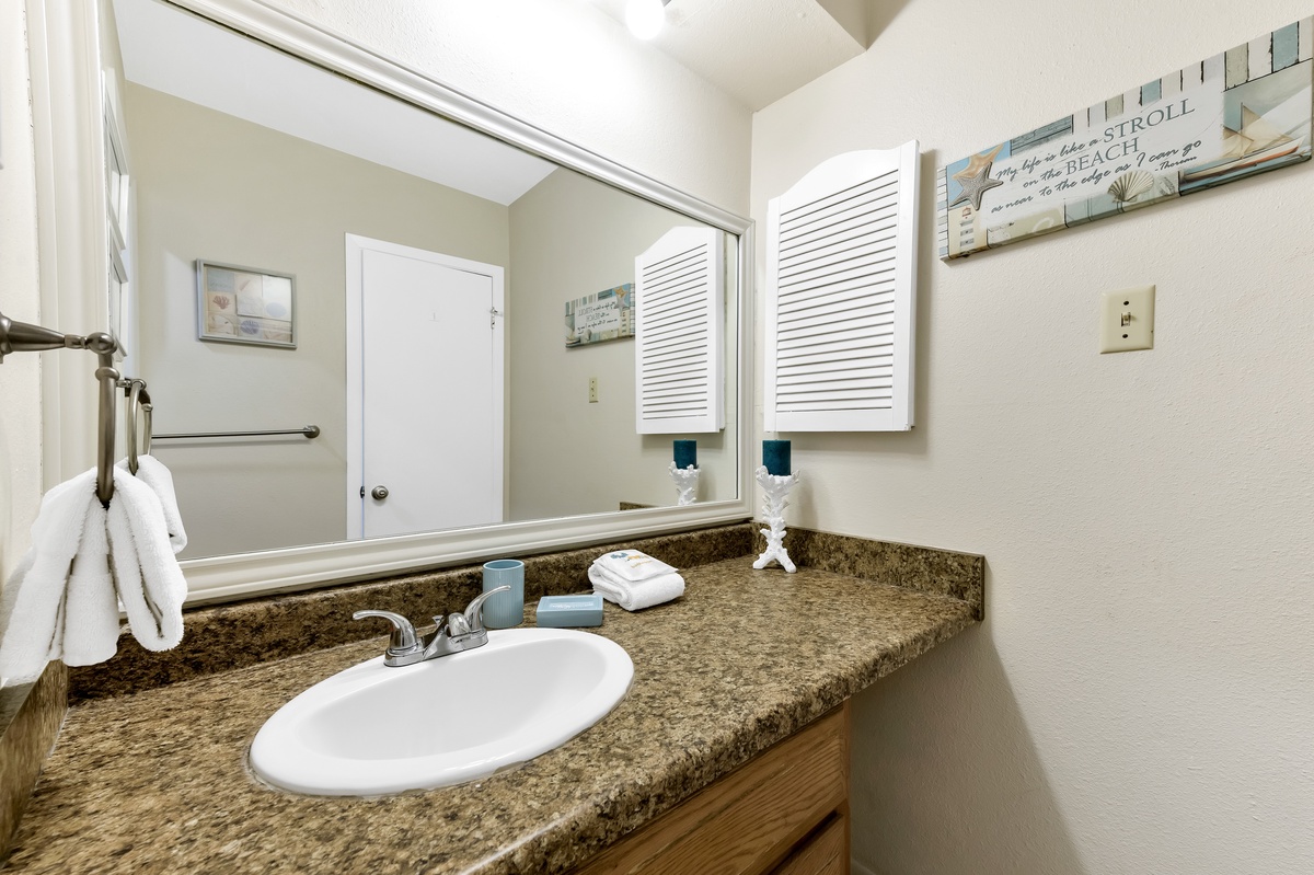 Step into your private bathroom featuring granite countertops, fluffy towels, and beach-themed touches that set a relaxing coastal mood.