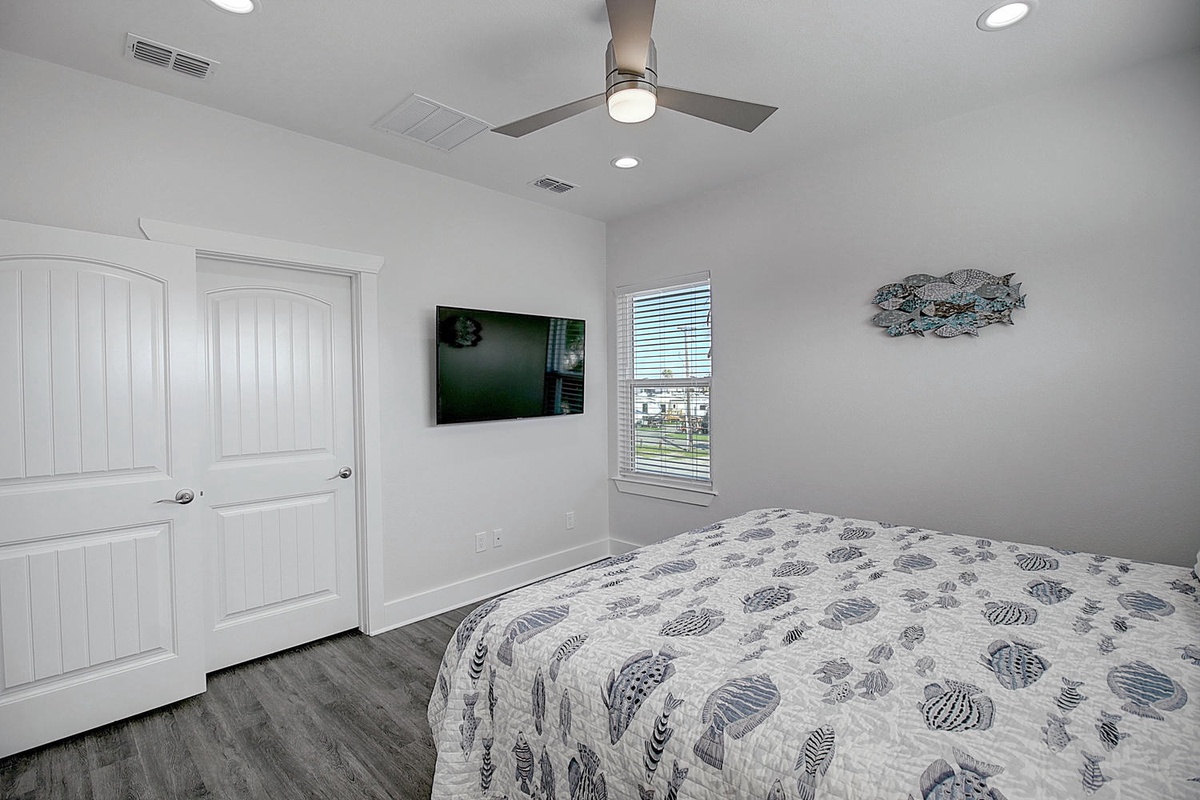 Unwind in your peaceful bedroom with soft coastal colors, modern ceiling fan, and street views from your window.