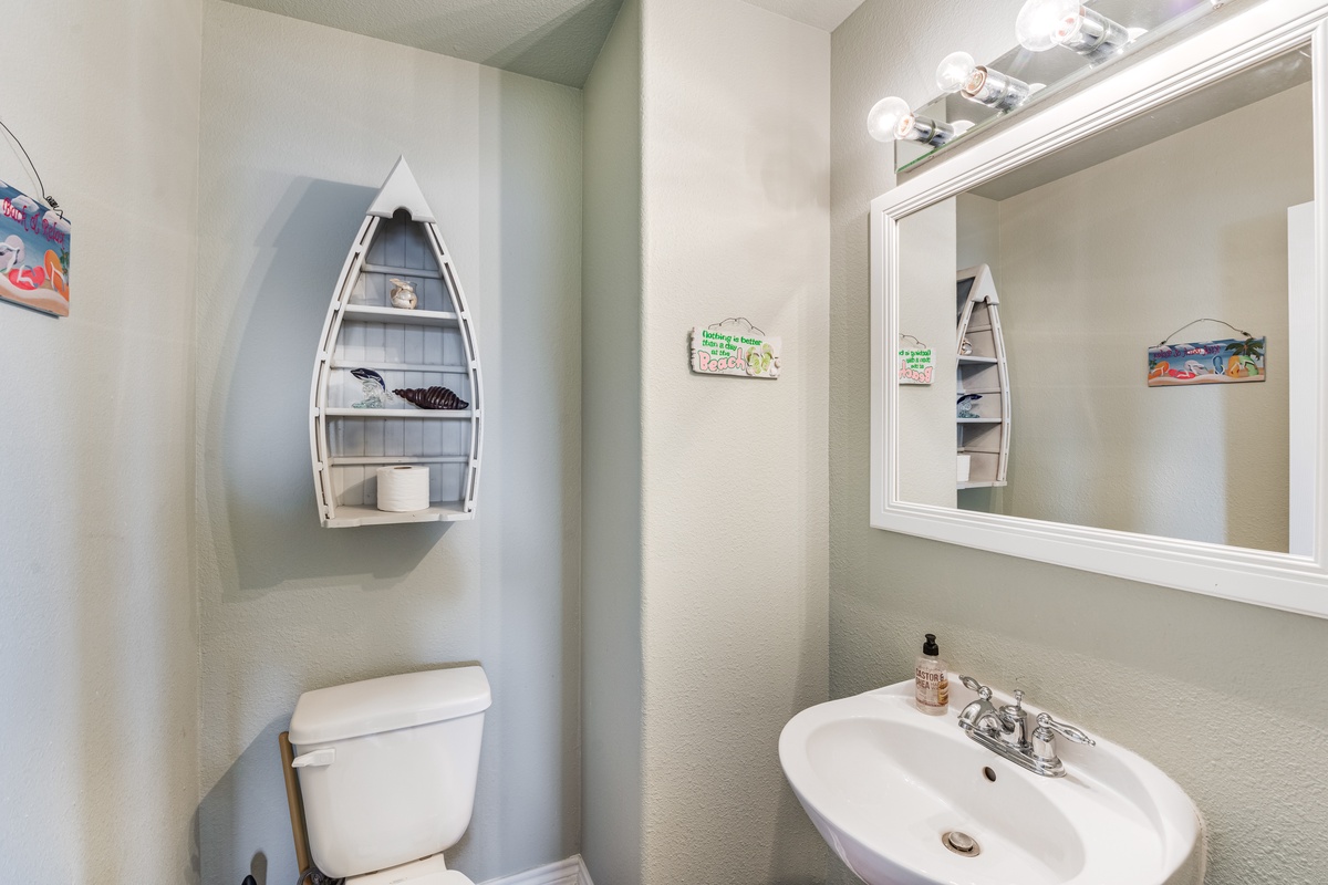 Step into your charming coastal-themed bathroom where nautical boat shelves and ocean artwork create a seaside sanctuary for your refreshing moments.