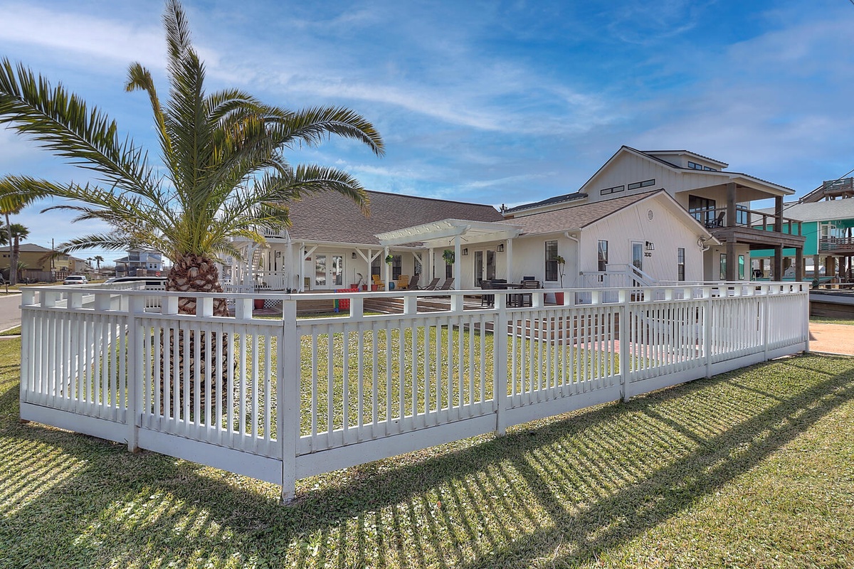 Charming beachside property with white picket fence and tropical palm trees in a peaceful coastal neighborhood.