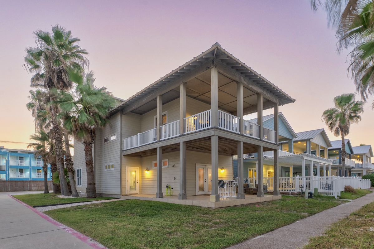 Modern beach house with wraparound balconies and tropical palms creates the perfect coastal retreat setting.