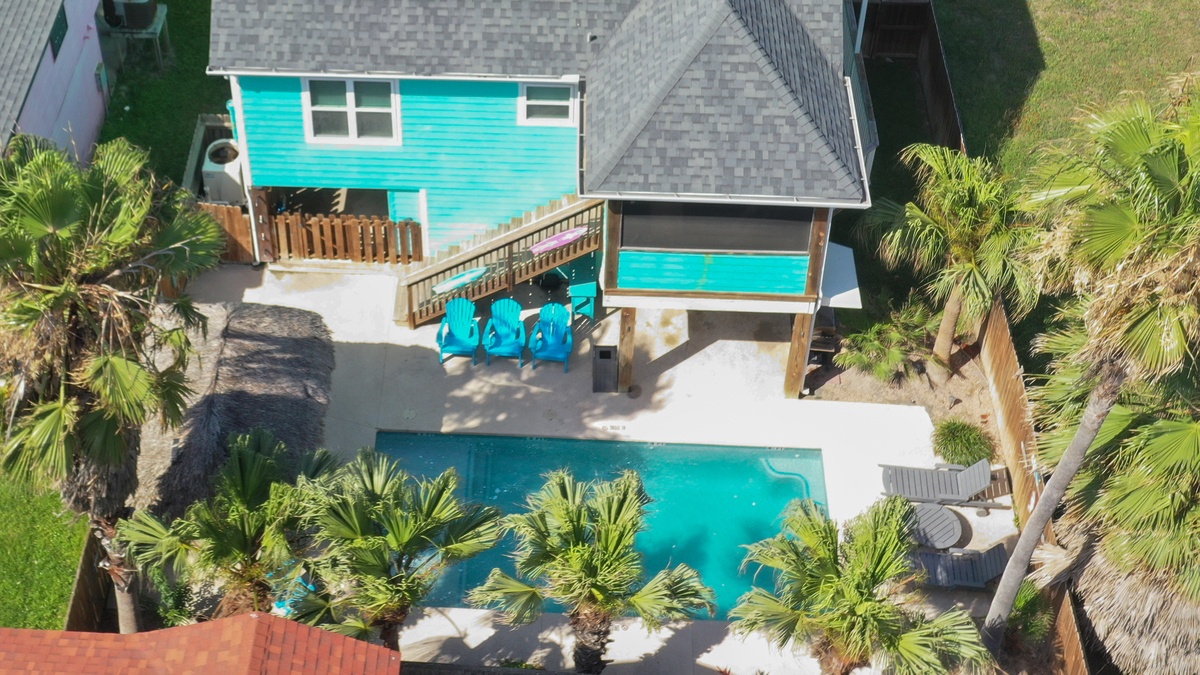 Aerial view of tropical vacation property featuring turquoise cottage, private pool, and lush palm trees creating a secluded island retreat.