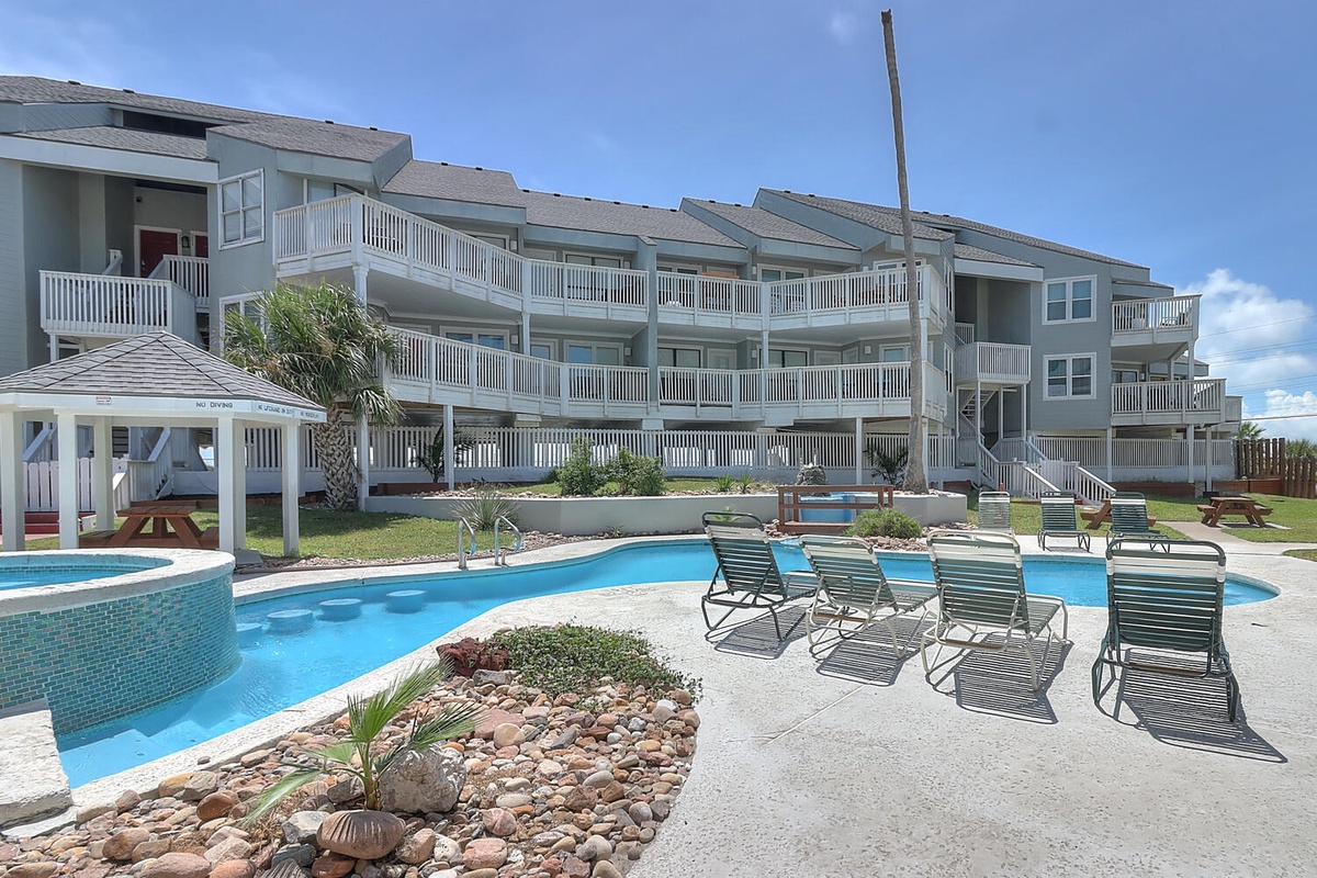Modern beachside condominium complex featuring multiple floors with private balconies and a resort-style swimming pool area.