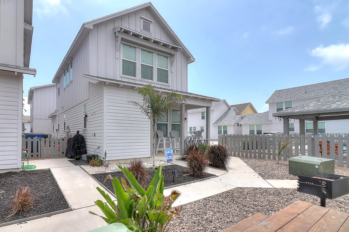 Modern coastal home with landscaped front yard and outdoor shower station in a quiet residential neighborhood.
