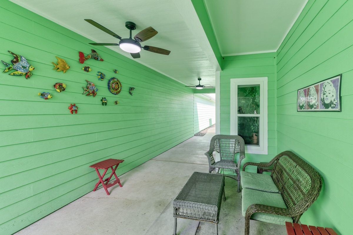 Relax on your private covered porch with comfortable wicker seating, where tropical fish art and cooling fans create your perfect coastal retreat.