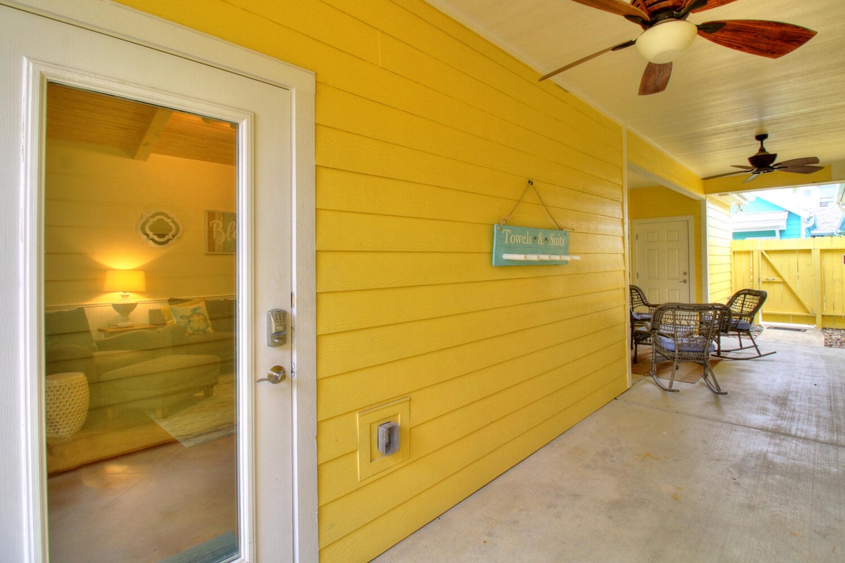 Your covered porch welcomes you with warm yellow walls and comfortable wicker seating for peaceful morning coffee or sunset relaxation.
