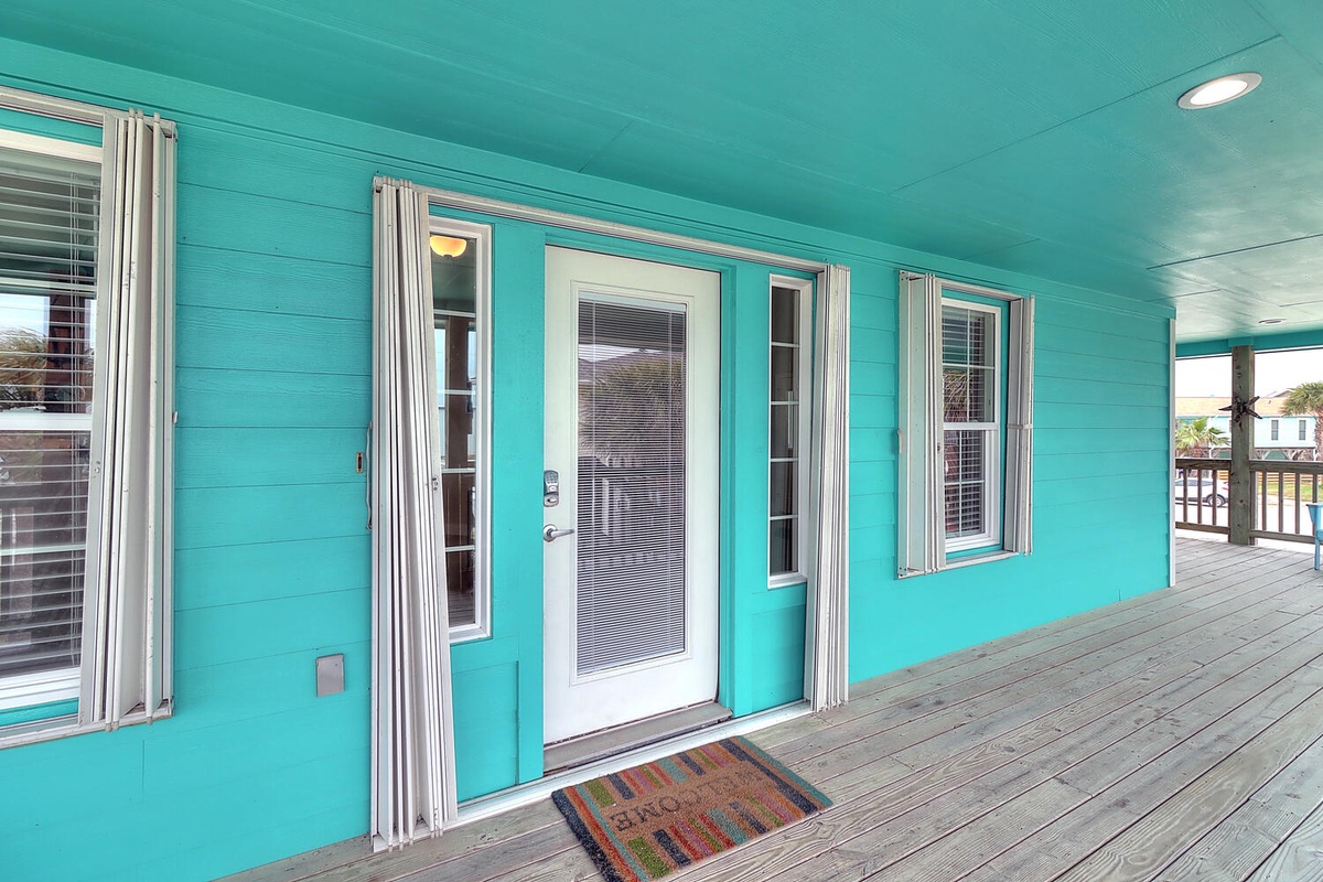 Bright turquoise exterior with welcoming front door and spacious covered deck for your coastal getaway.