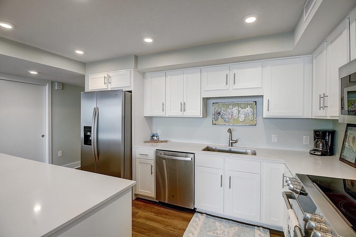 Your bright, modern kitchen features pristine white cabinets, quartz countertops, and stainless steel appliances—perfect for preparing memorable meals.