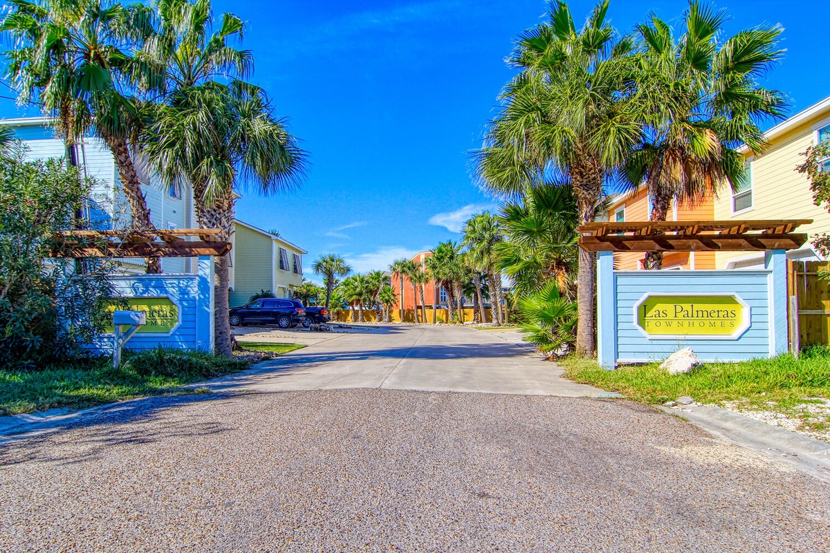 Welcome to Las Palmeras Townhomes, a tropical oasis where swaying palm trees frame colorful vacation rentals under endless blue skies.