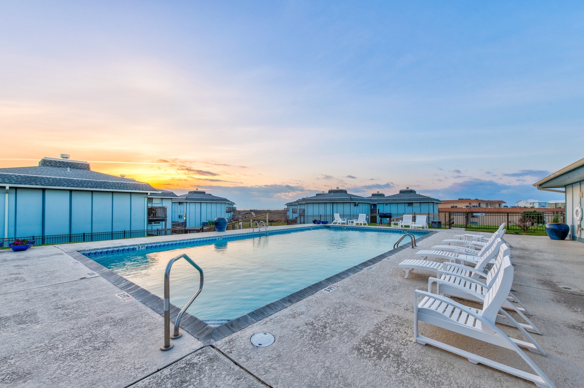 Stunning community pool with dramatic sunset backdrop creates the perfect setting for evening relaxation and vacation memories.