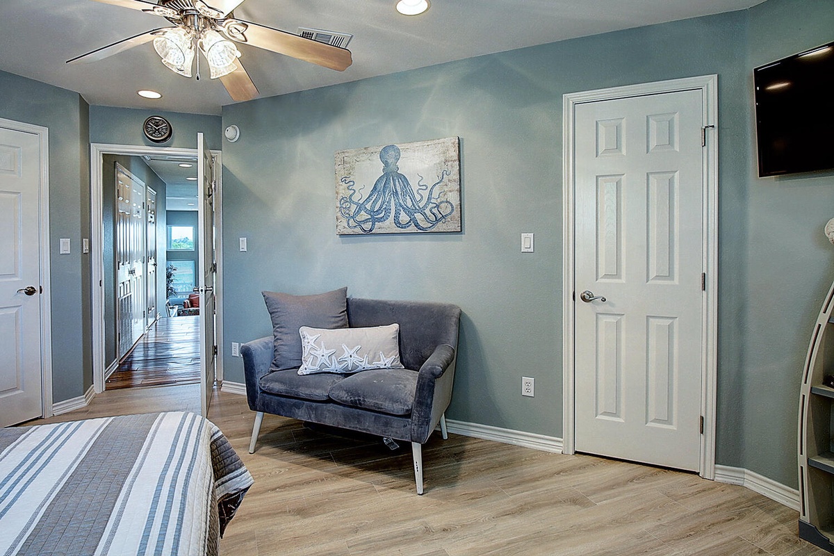 Unwind in your peaceful coastal bedroom with charming octopus art, comfy seating, and soothing blue tones that create the perfect beachside retreat.
