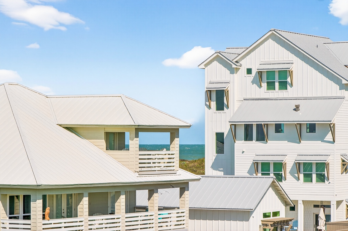 Modern coastal vacation homes with ocean views, featuring bright white exteriors and charming green shutters just steps from the beach.