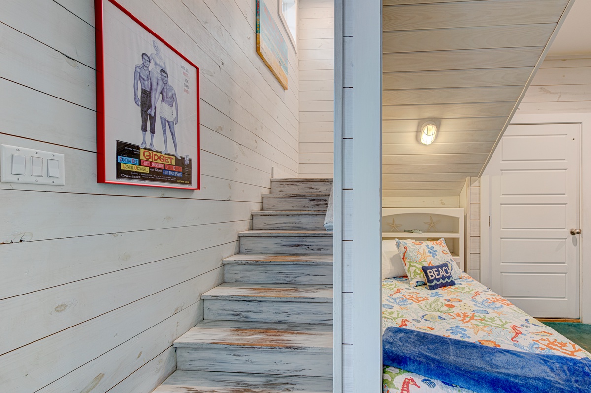 Cozy under-stair nook with twin bed creates your perfect reading retreat in this charming coastal cottage.
