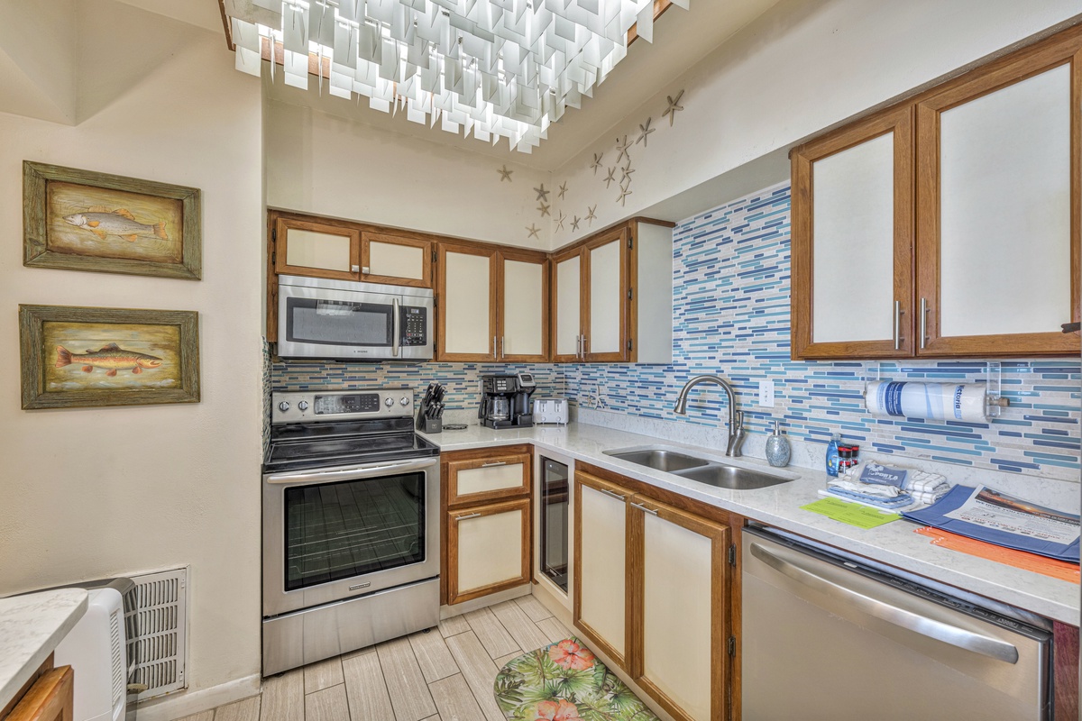 Your coastal-themed kitchen features ocean-blue mosaic backsplash, stainless appliances, and charming fish artwork for inspired seaside cooking.