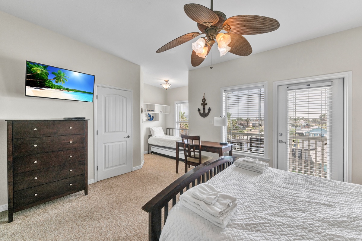Unwind in your bright bedroom with tropical ceiling fan, flat-screen TV, and peaceful neighborhood views through large windows.