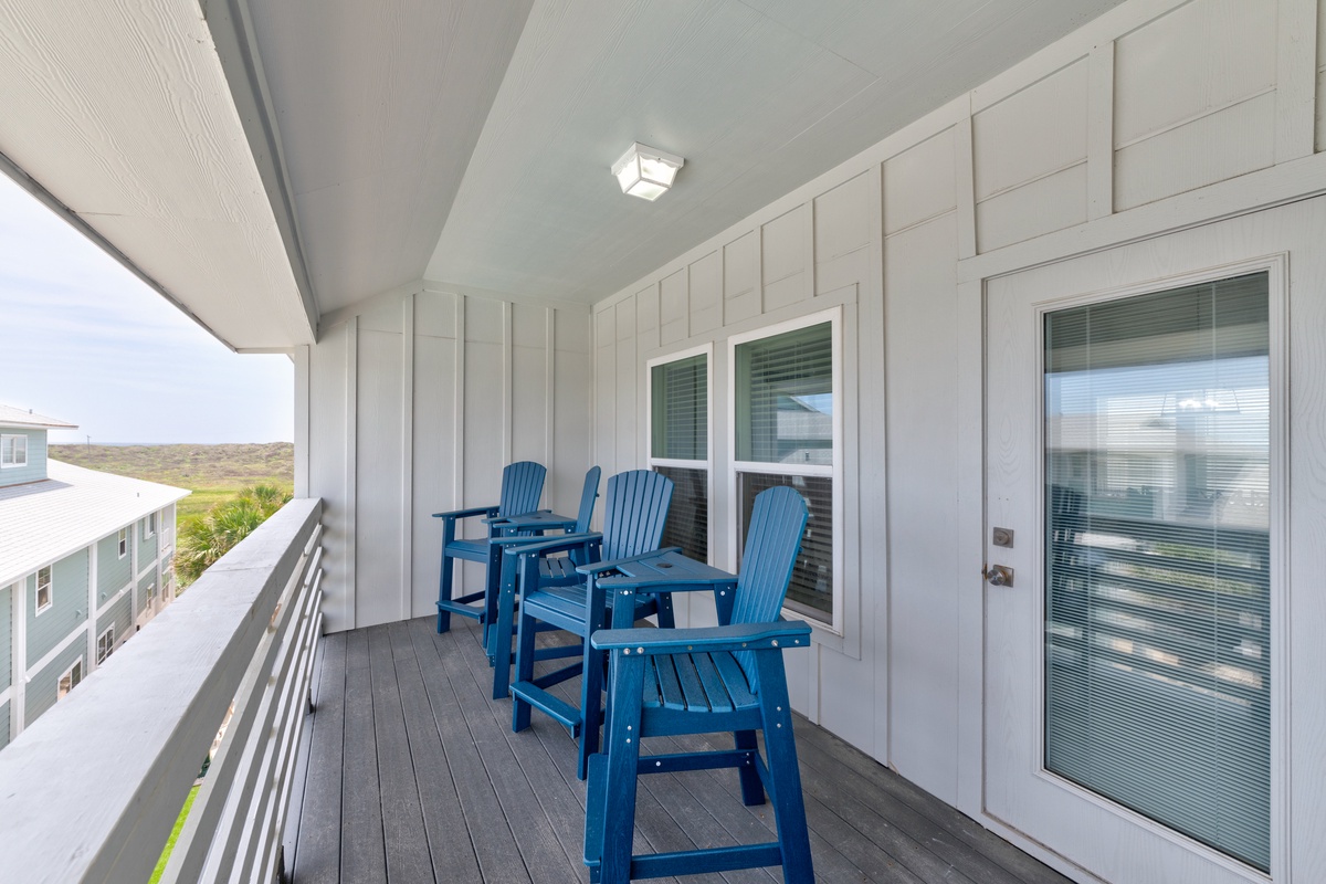 Relax on your private covered balcony with comfortable blue Adirondack chairs overlooking coastal views—perfect for morning coffee or evening sunsets.