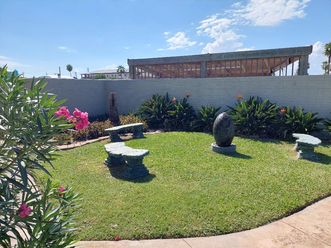 Step into your private garden sanctuary with lush lawn, decorative stone seating, and vibrant tropical plants creating the perfect outdoor retreat.
