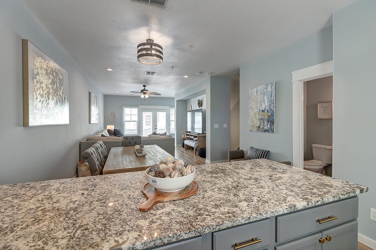 Relax in your elegant open-plan living space featuring granite countertops, modern furnishings, and soothing coastal colors throughout.