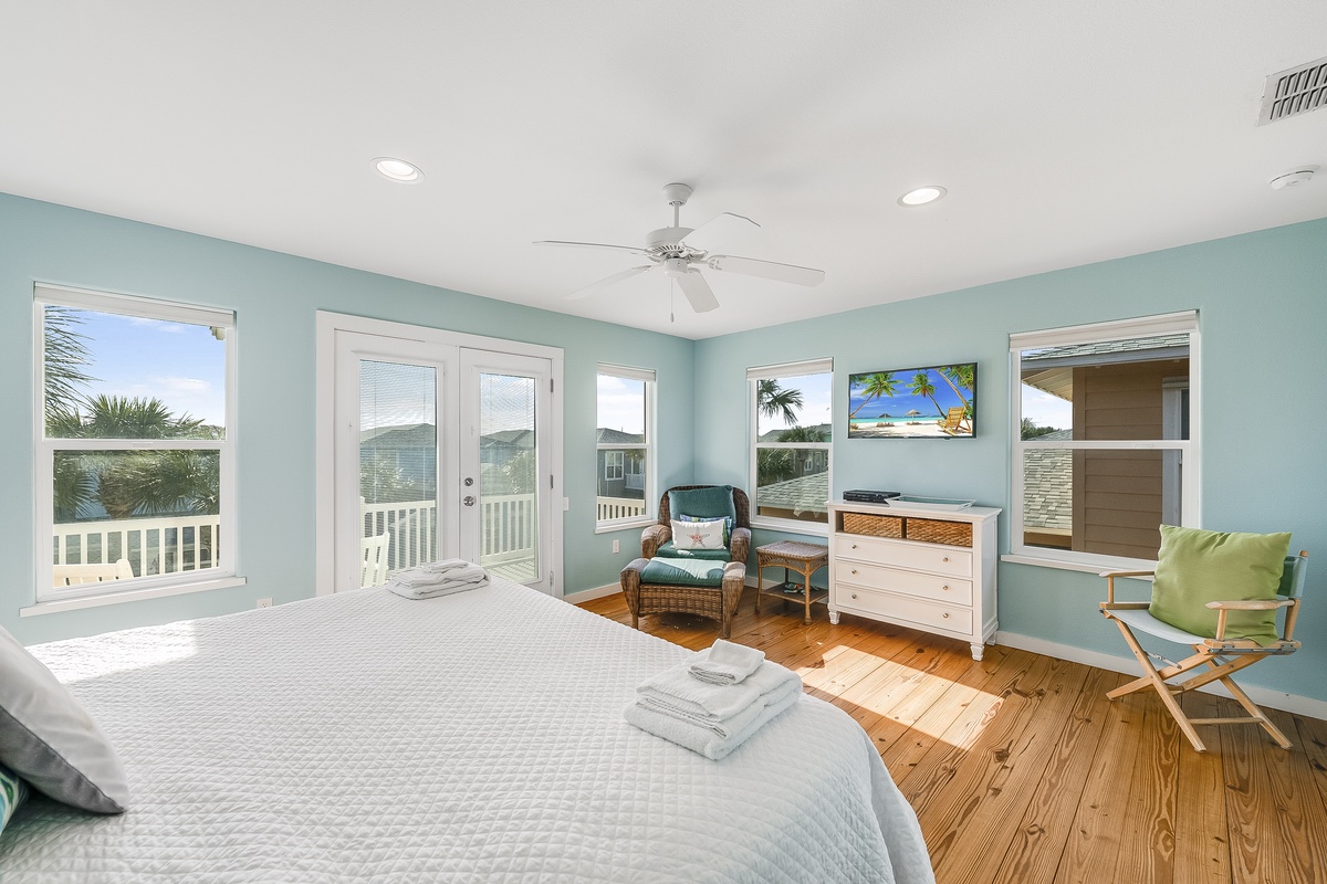 Your serene bedroom sanctuary features soothing coastal colors, warm hardwood floors, and French doors opening to your private balcony with tropical views.