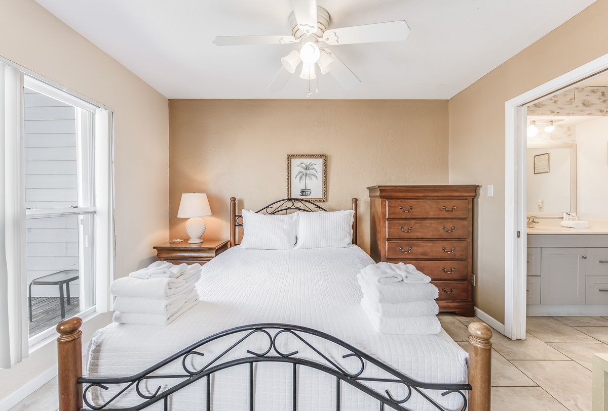 Relax in your serene bedroom with crisp linens, warm wood furnishings, and gentle ceiling fan keeping you comfortable.