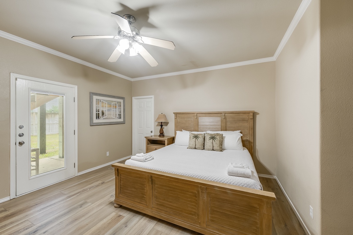 Unwind in your serene bedroom featuring a cozy wooden bed, fresh linens, and gentle ceiling fan for perfect comfort.