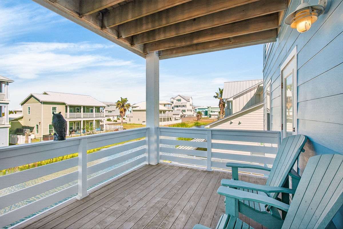 Unwind on your private covered balcony with cozy seating, where coastal breezes and neighborhood views create the perfect spot for morning coffee or evening relaxation.